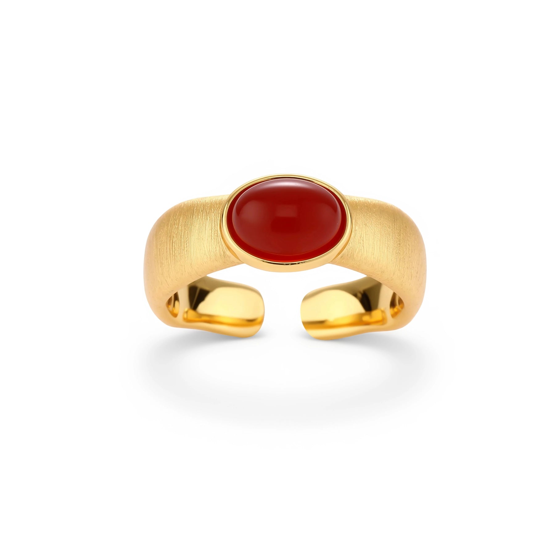 Close-up of brushed gold-plated ring with deep red oval stone, featuring adjustable band design on neutral background.