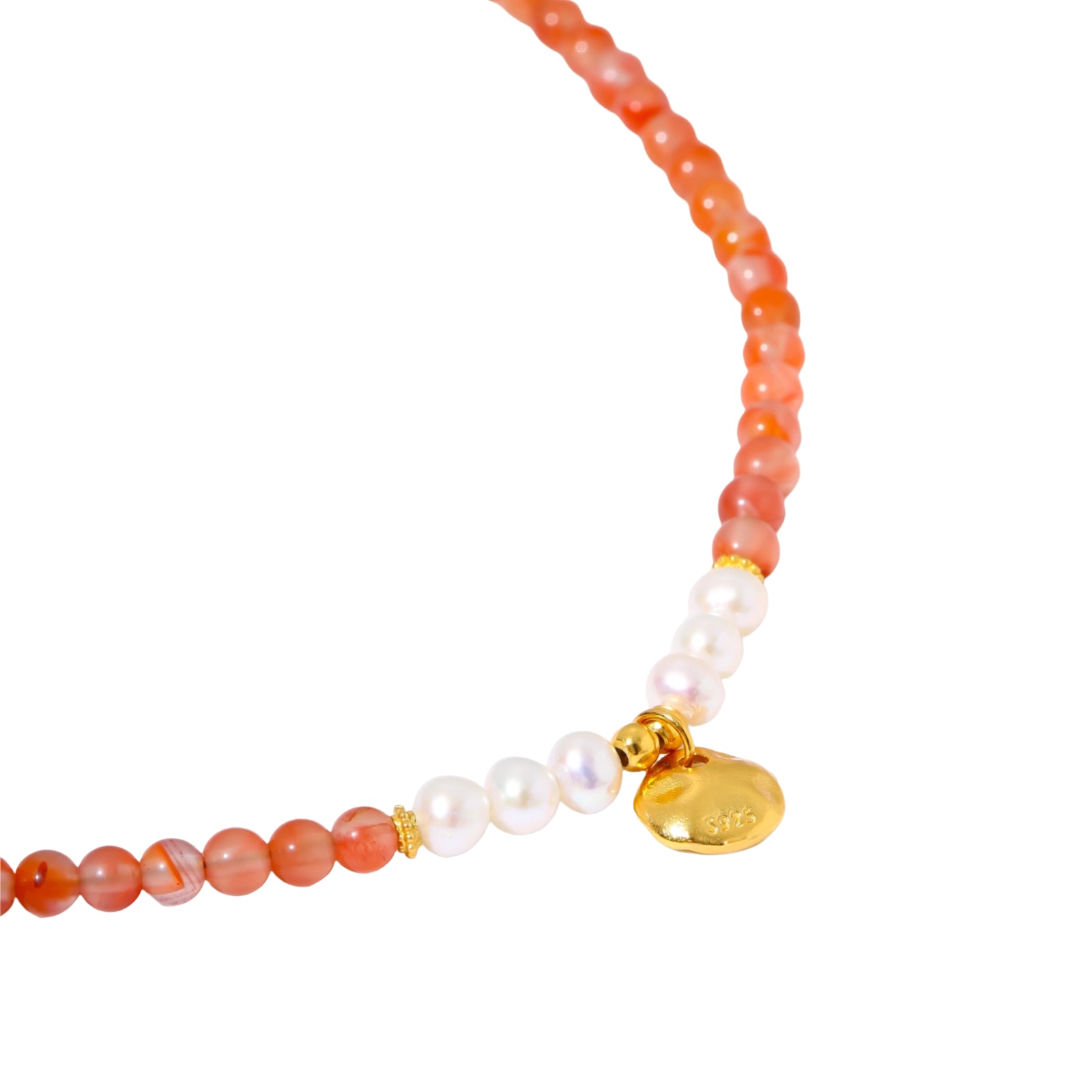 Beaded bracelet with coral-orange carnelian stones, white pearls, and gold heart charm on cream background