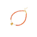 Beaded bracelet with coral-orange carnelian stones, white pearls, and gold heart charm on cream background