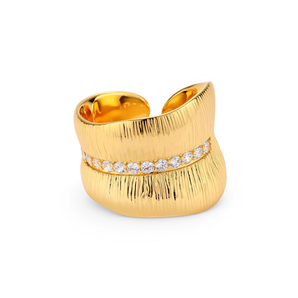 Adjustable gold-plated cuff ring with parallel ridged texture and diagonal row of sparkling zirconia stones on white background.